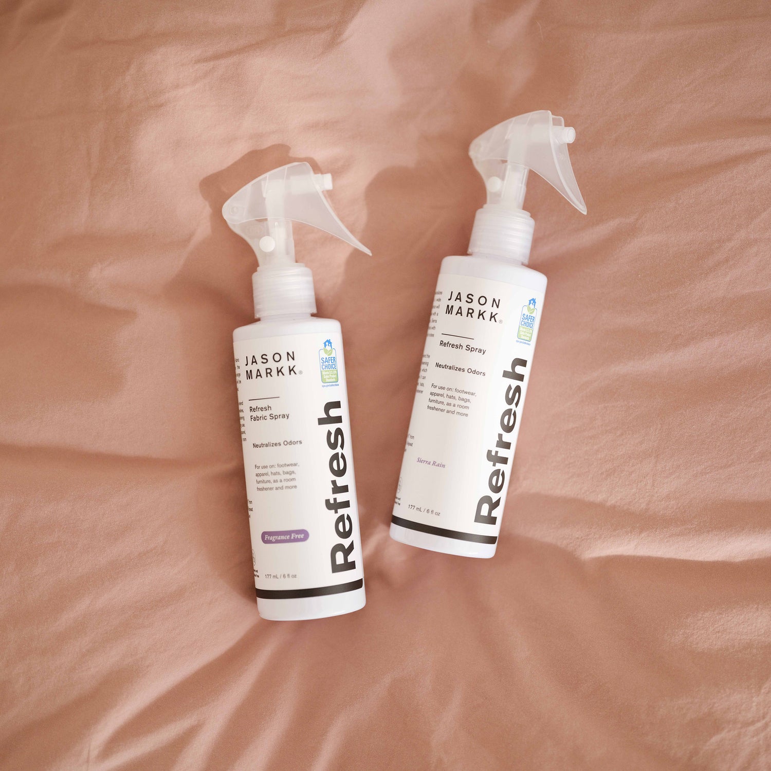 Photo showing the Sierra Rain and Fragrance Free versions of Refresh Spray on top of bedsheets.