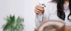 Woman spraying Ugg with Repel Spray, then opening a Quick Wipe at a table, then spraying a bed with Refresh Spray.