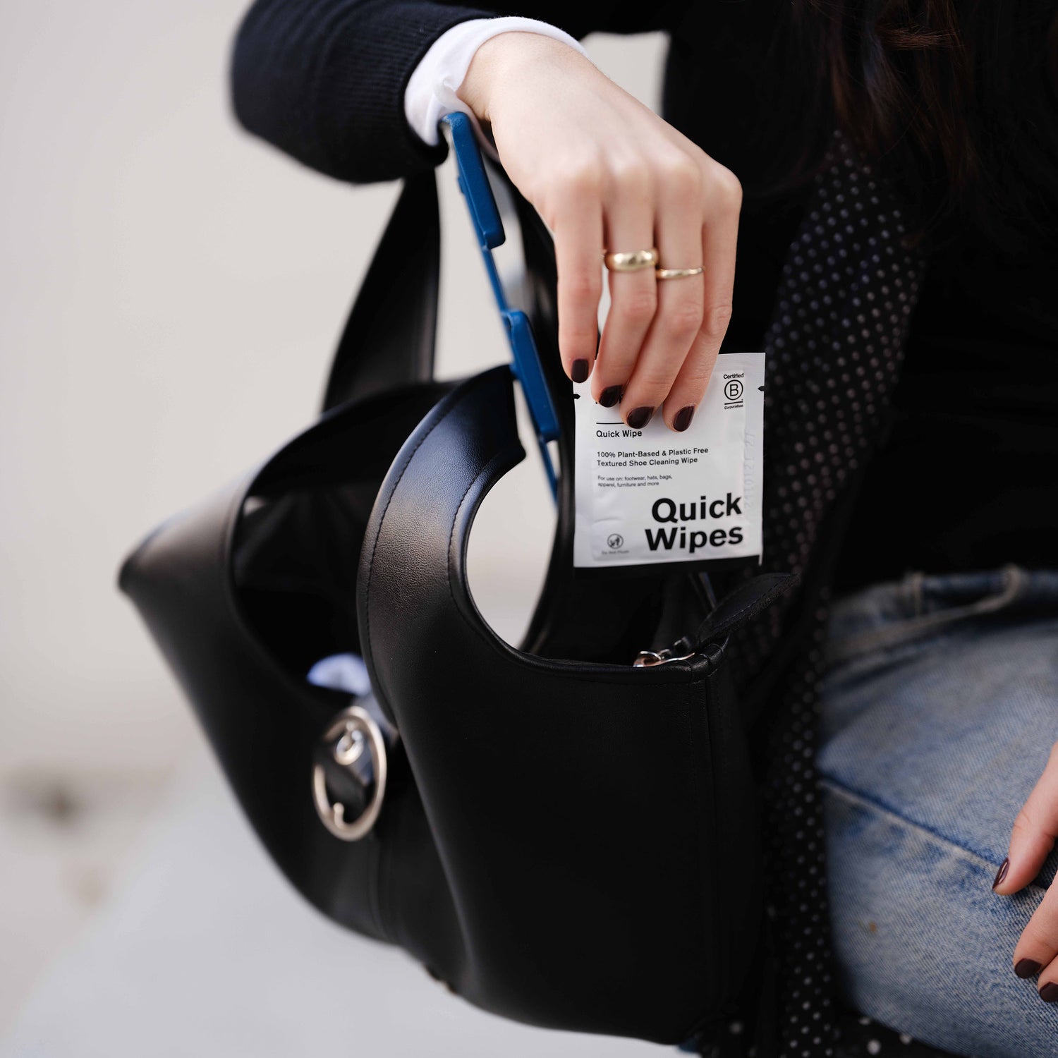 A photo of a woman pulling out an individually packed Jason Markk Quick Wipe from her purse.