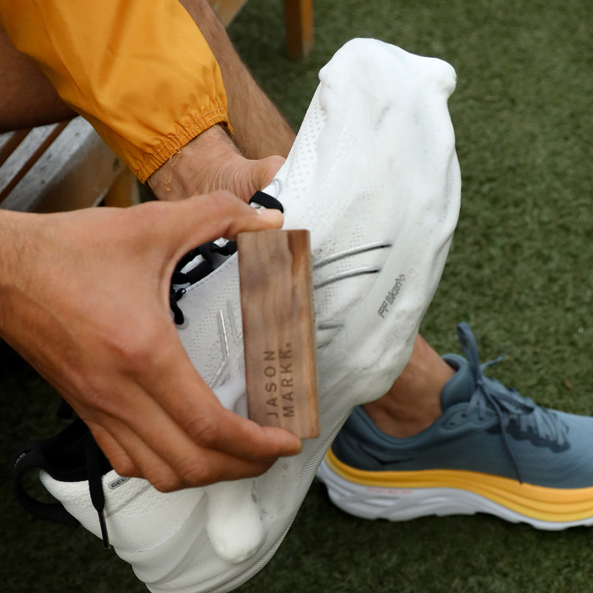 A photo of someone cleaning a pair of Asics with Jason Markk RTU Foam and a Delicates Brush