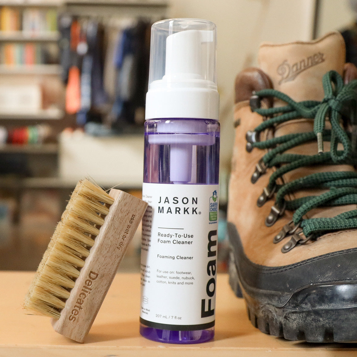 A photo of Jason Markk Delicates Brush and RTU Foam sitting next to Danner Boots