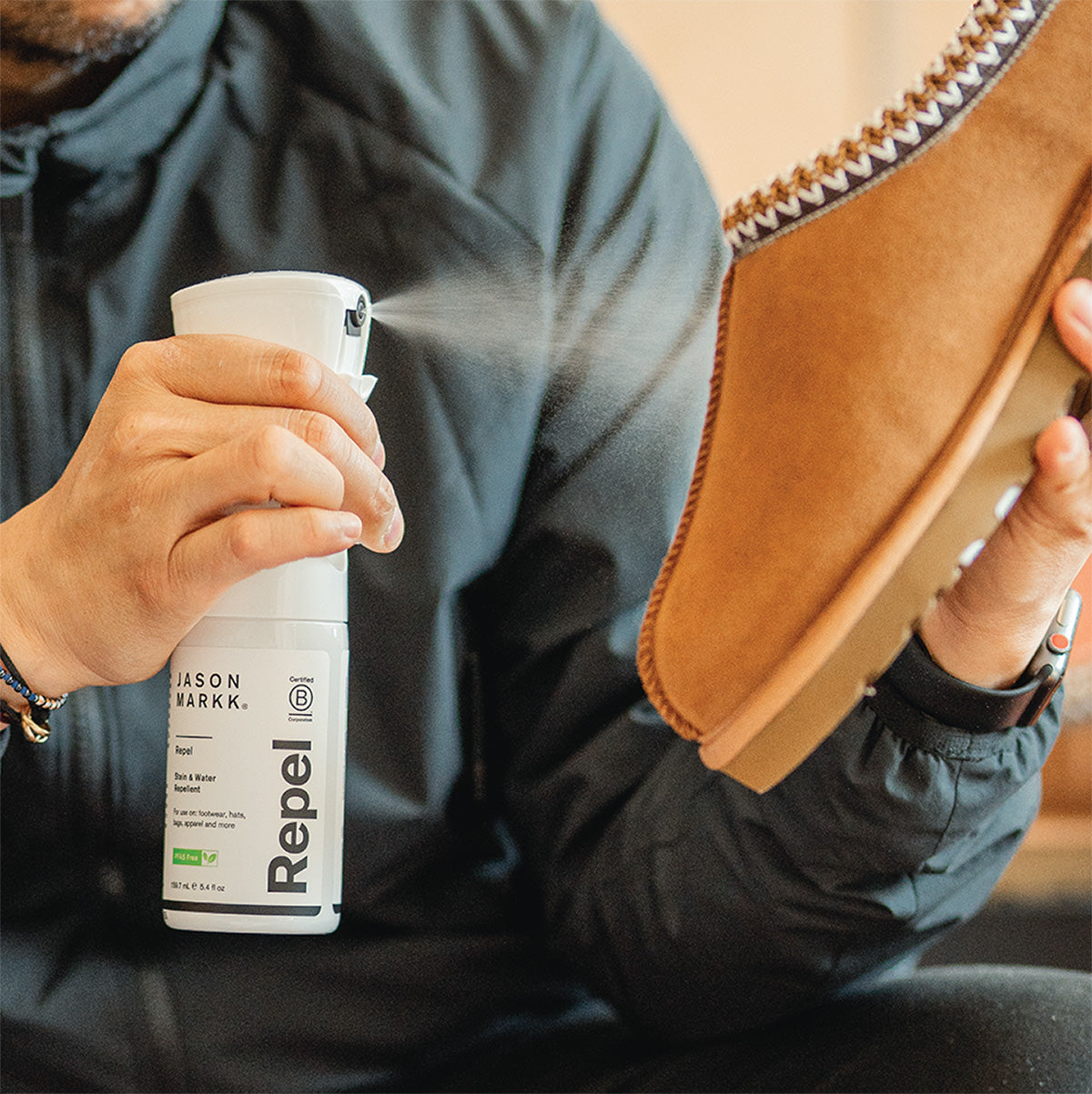 A photo showing a man using Jason Markk Repel Spray on Ugg Tasman