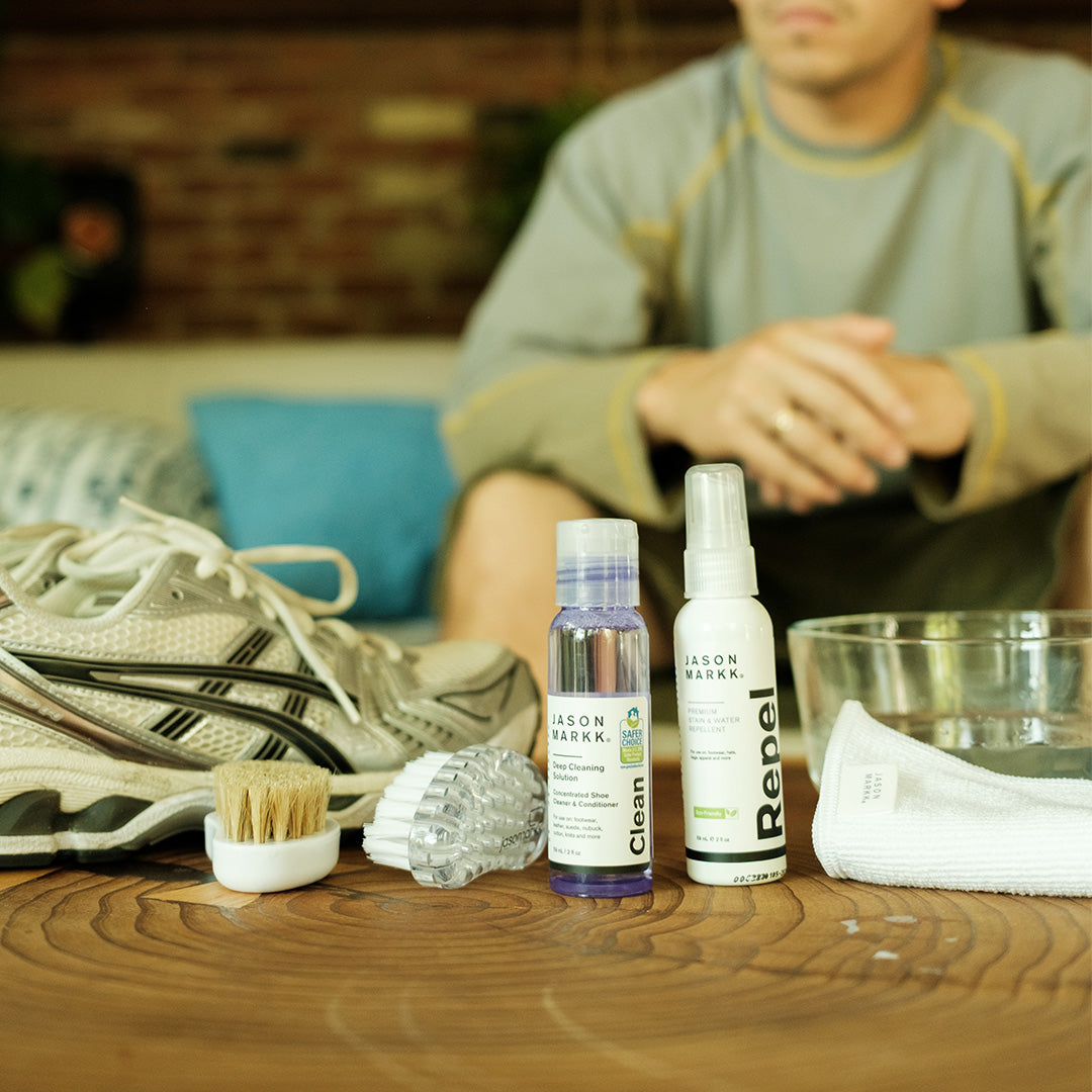 Person sitting on a couch with cleaning products and shoes on a table in front of them.