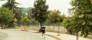 A photo of a man running on street with trees in background