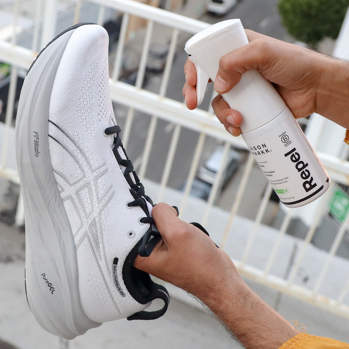 Person holding a white sneaker and a spray bottle Repel outdoors.