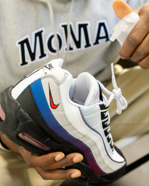 Person spraying a nike running shoe with Refresh Spray