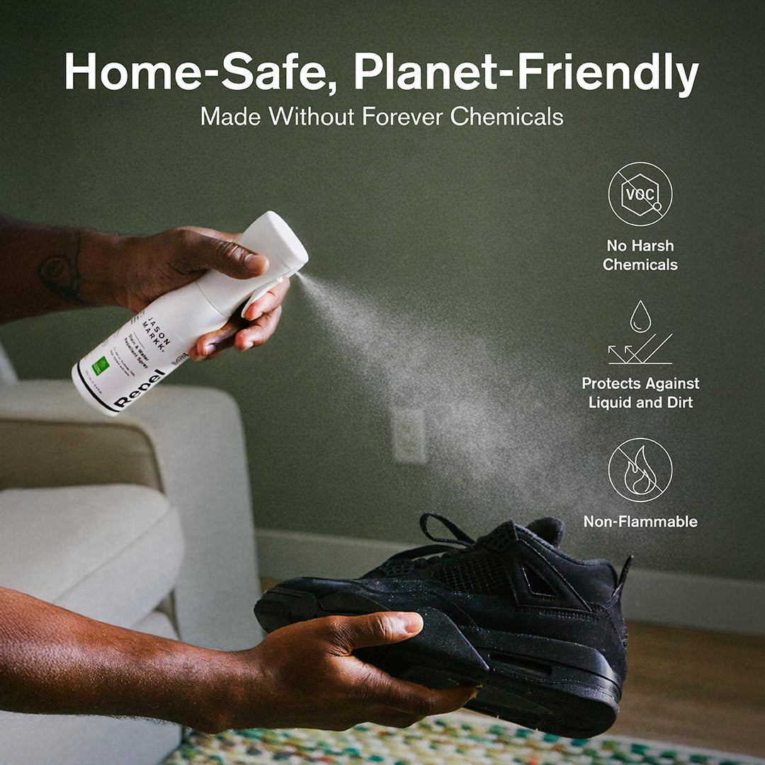 A person spraying Jason Markk Repel stain and water repellent directly onto a pair of all-black Jordan 4 sneakers in a home setting. Three feature icons on the right highlight: No Harsh Chemicals (VOC-free), Protects Against Liquid and Dirt, and Non-Flammable. Text overlay reads: "Home-Safe, Planet-Friendly – Made Without Forever Chemicals."