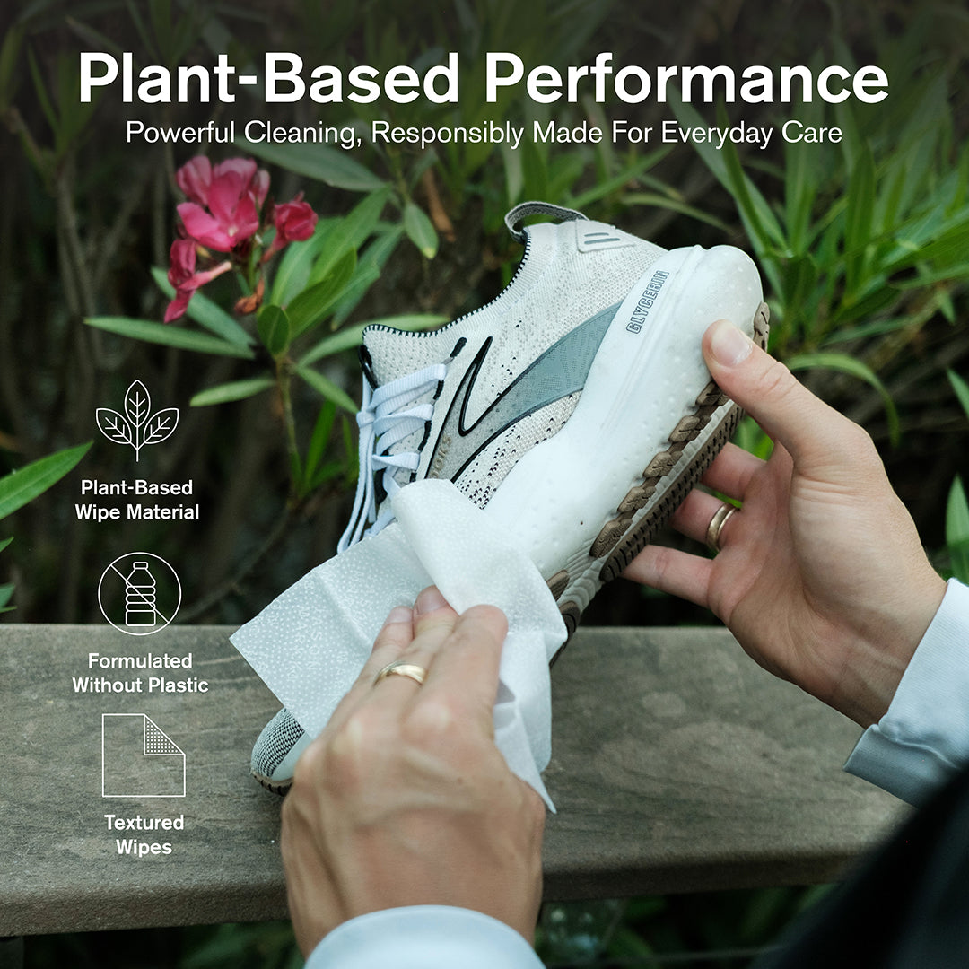 Person cleaning a shoe with a plant-based Quick Wipe, surrounded by greenery.