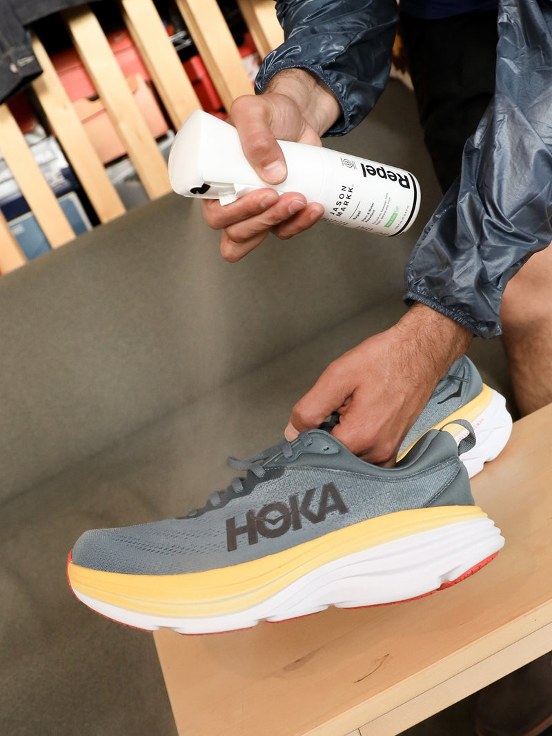 Person spraying a pair of running shoes with Repel