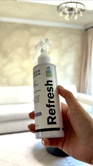 Hand holding a bottle of Refresh Fragrance Free spray
