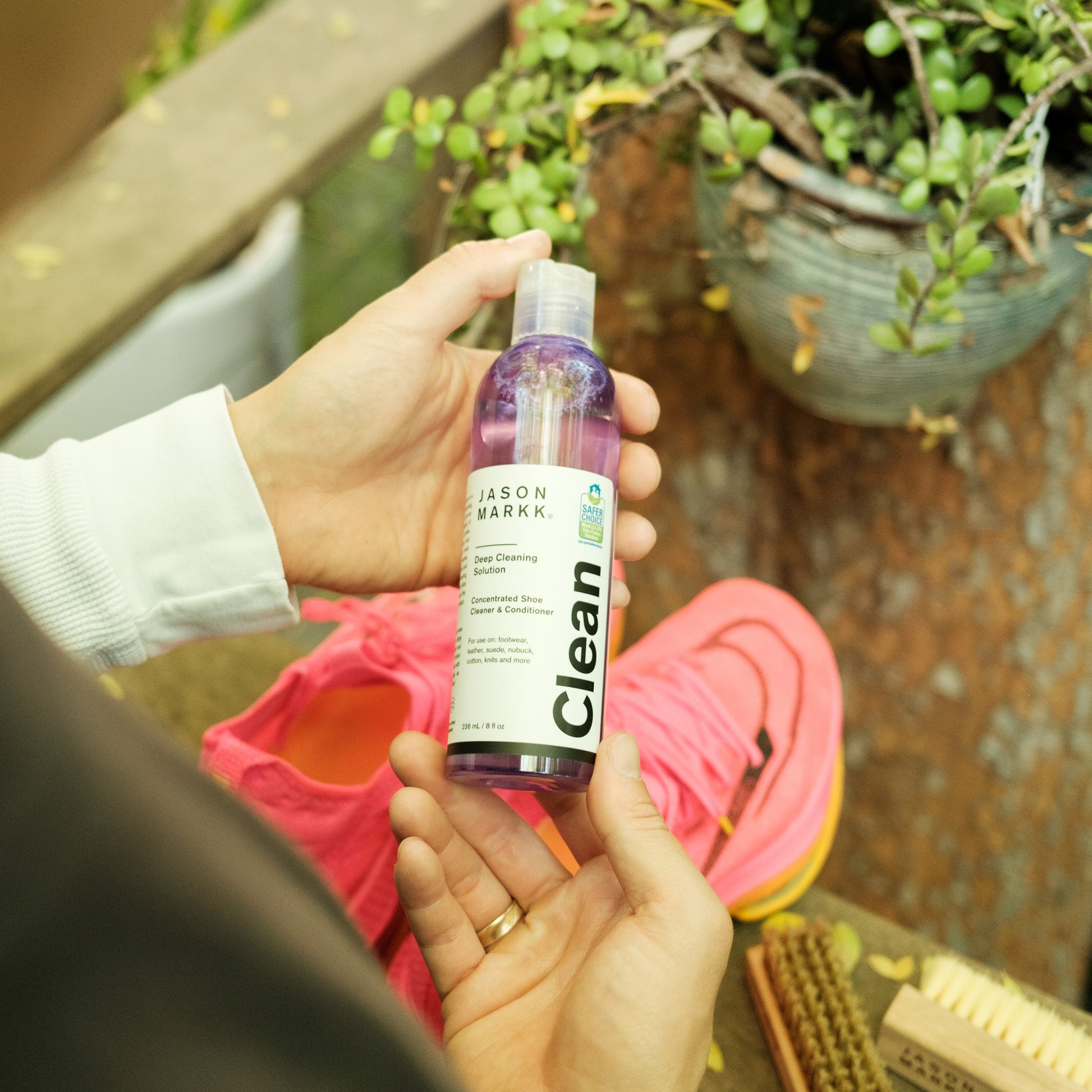 JASON MARKK DEEP CLEANING SOLUTION HELD OVER NIKE RUNNING SHOES OUTSIDE