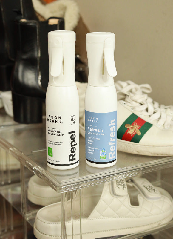 Jason Markk Repel Stain & Water Repellent Spray and Refresh Odor Neutralizer bottles displayed on a clear acrylic shoe shelf. Refresh label reads: Lightly Scented, Hemp, Rain. For footwear, hats, and apparel. Safer Choice certified. Styled alongside white Gucci sneakers and designer shoes. Essential shoe care products for sneaker collectors and footwear enthusiasts.