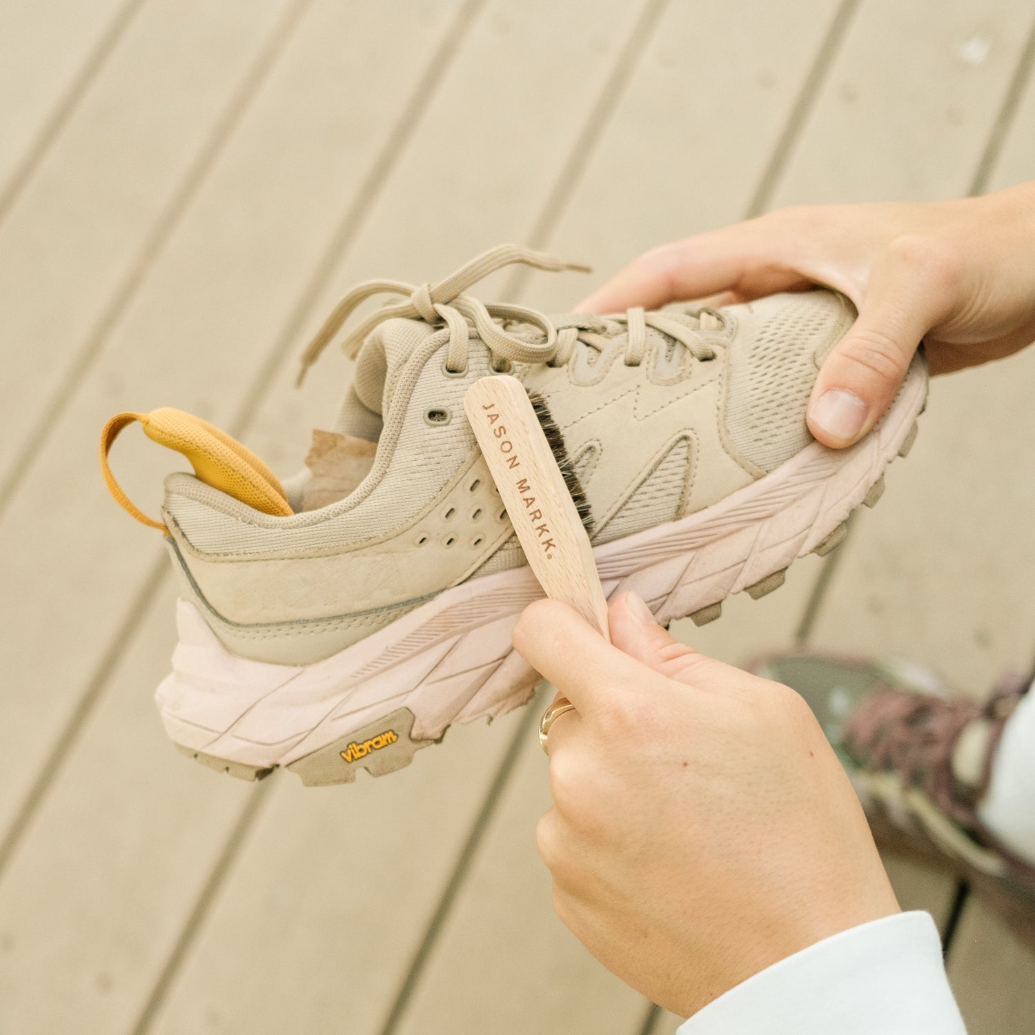 A JASON MARKK SUEDE CLEANING BRUSH BEING USED ON A PAIR OF HOKA HIKING SHOES