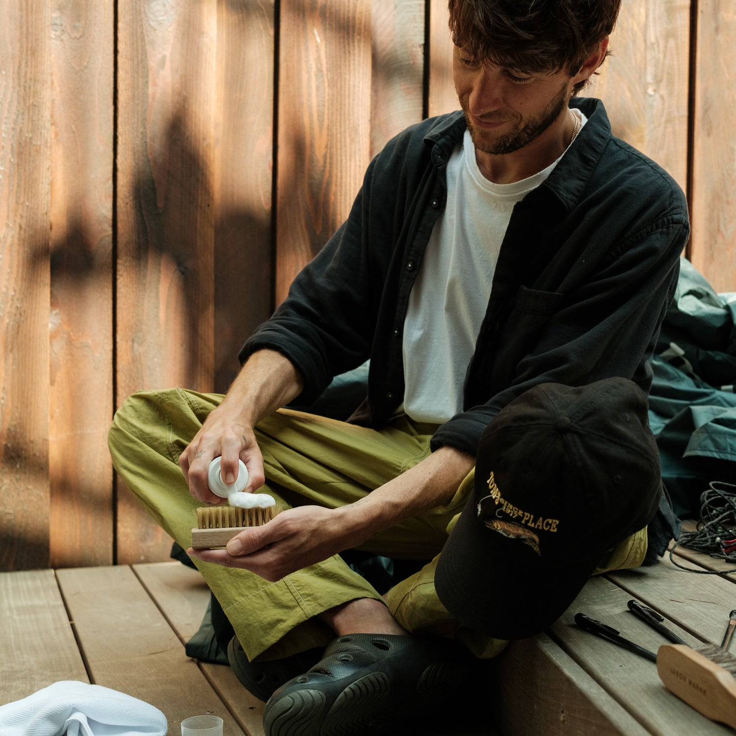 A MODEL APPLYING JASON MARKK HAT FOAM CLEANER ON A DELICATES BRUSH