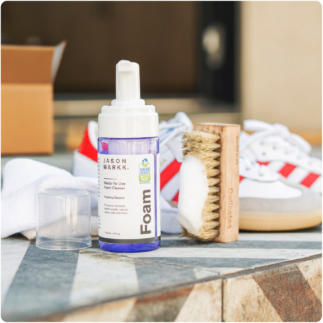 Bottle of Jason Markk RTU Foam with cleaning tools on a porch