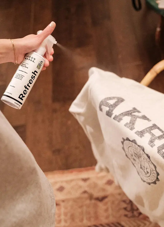 Person using Refresh Spray on a white sweatshirt.