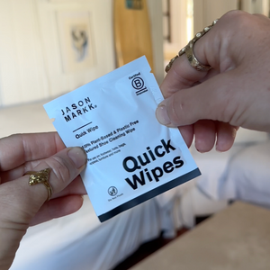 Hands holding a package of Jason Markk Quick Wipes with a blurred background.