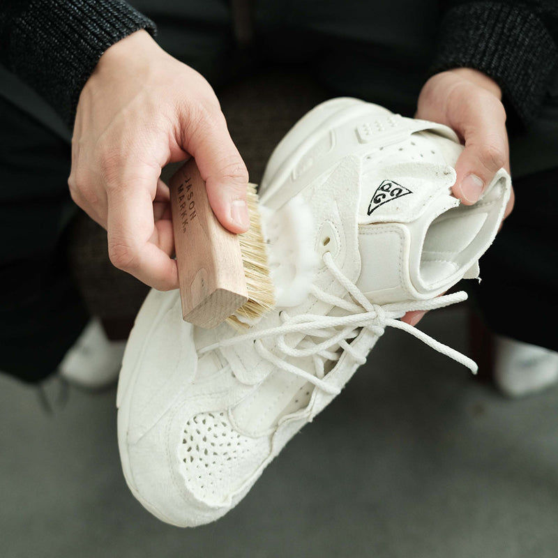 Person cleaning a white sneaker with a Delicates Brush