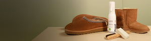 Jason Markk Repel Stain & Water Repellent Spray (5.4 fl oz) displayed alongside a suede brush and eraser block, styled with chestnut UGG-style slip-on slippers and short suede boots on a neutral surface with a sage green background. Ideal for protecting suede footwear, nubuck, and delicate materials.
