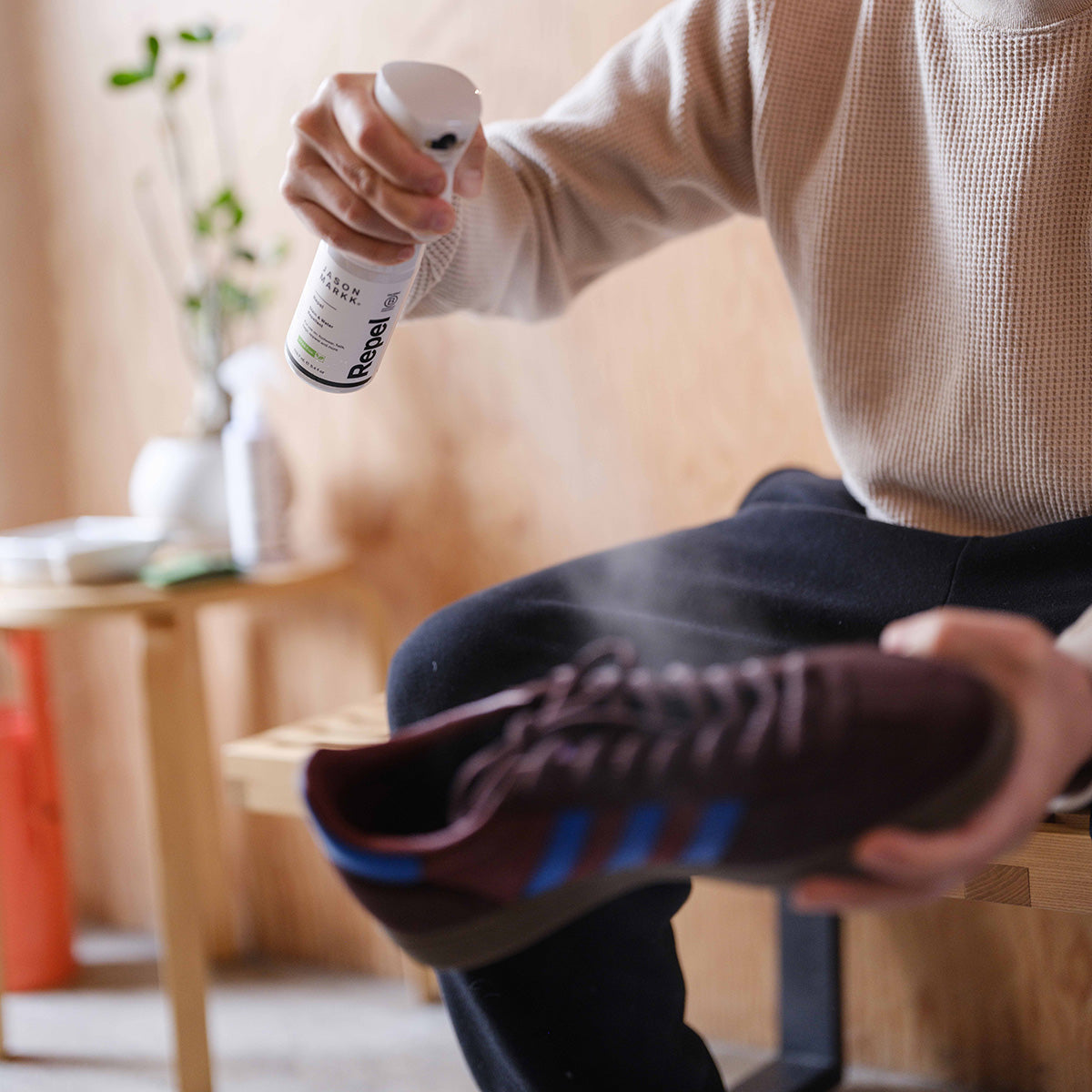 A photo of a man spraying an Adidas shoe with Jason Markk Repel Spray