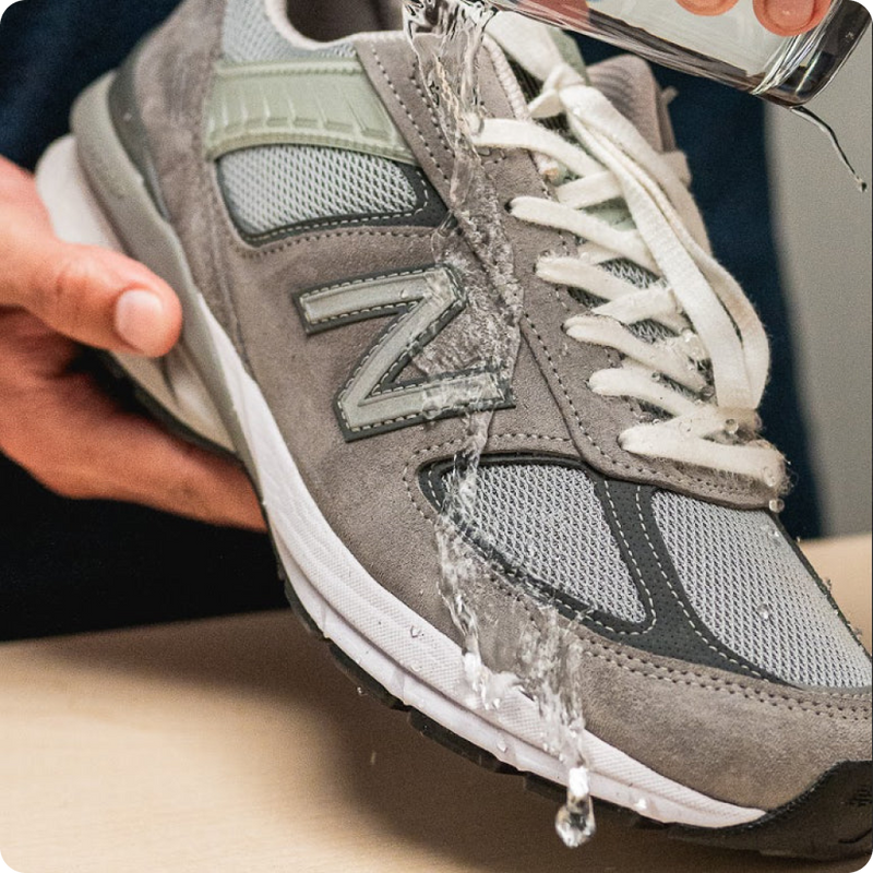 Gray sneaker with water being poured onto it, showing water resistance because of using Jason Markk Repel.