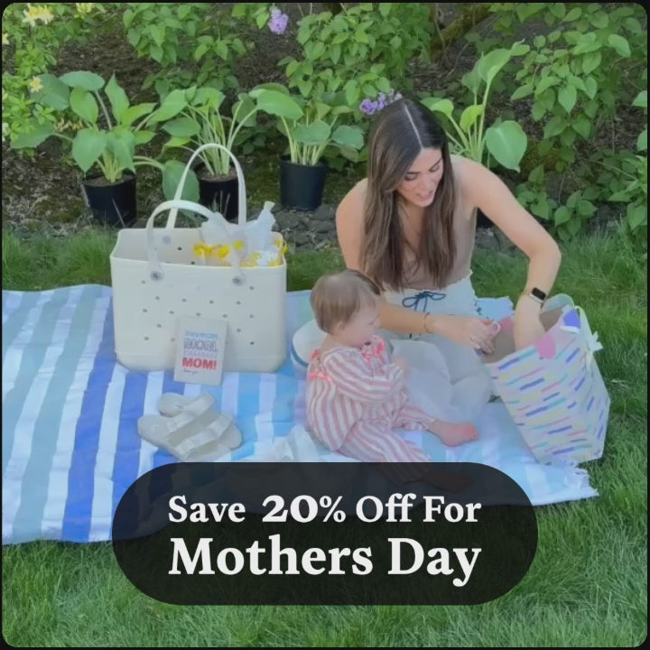 Video of a mom sitting on a striped blanket outdoors with her baby, surrounded by a white tote bag and Mother's Day gifts. Text overlay reads: "Save 20% Off For Mothers Day." Shop Jason Markk's Mother's Day sale and save 20% off premium shoe and accessory care products.